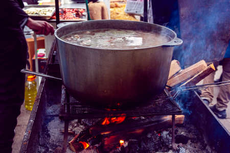 fresh-soup in a metal bowl from above over a fire is preparation food on a public placeの写真素材