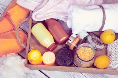 SPA consist from orange slippers, bathrobe, towels and other accessories for bath in a wooden trayの写真素材