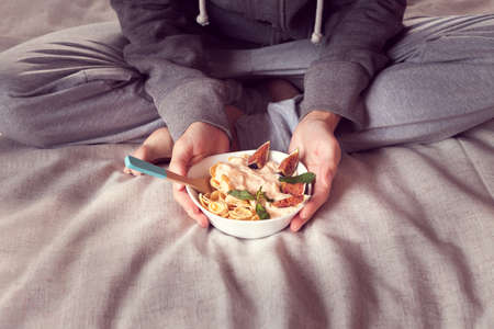 woman holds a bowl with diet cereal and figsの写真素材