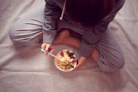 woman holds a bowl with diet cereal and figsの写真素材