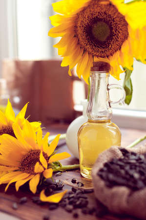 sunflowers seeds in a bag and oil with sunflowers on a wooden backgroundの写真素材