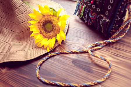 hat, bags and yellow sunflower on a wooden background
