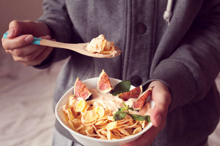 woman holds a bowl with diet cereal and figsの写真素材