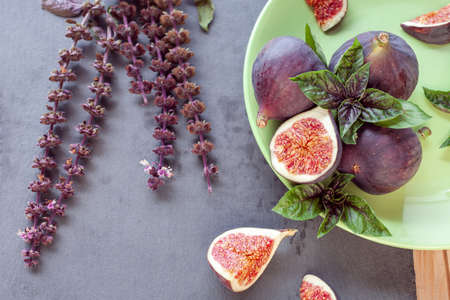 sliced figs with basil in green bowl on a dark backgroundの写真素材