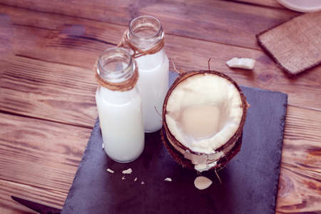 two half of  coconut and two bottles of coconut milk on a black backgroundの写真素材