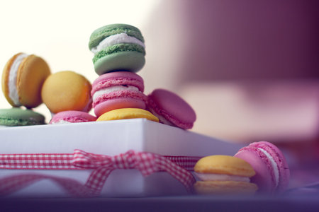 yellow, pink and green macaroons in a box with bow-knot