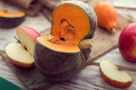 Slice of green pumpkin with slice of red apples on a sackclothの写真素材