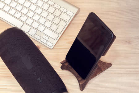 black portable speaker with mobile phone and white keyboardの写真素材