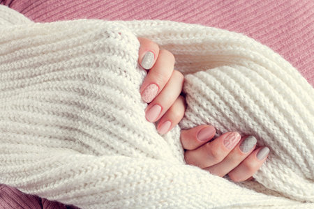 knitted texture manicure on nails from pink and gray colors with white scarf