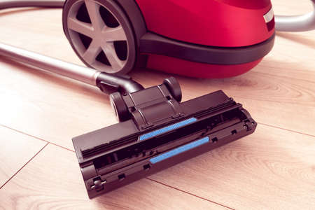 vacuum cleaner of red color on a gray laminateの写真素材