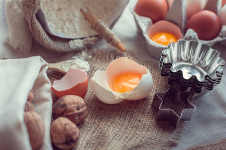 broken eggs, nuts, flour and baking tins on a sackcloth
