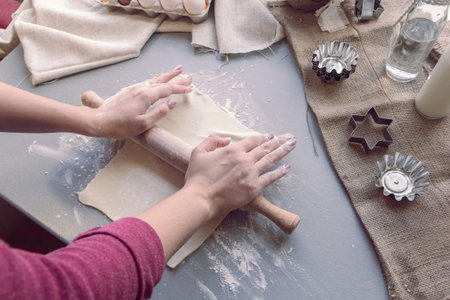 Preparation for baking cookies: female hands roll out the dough