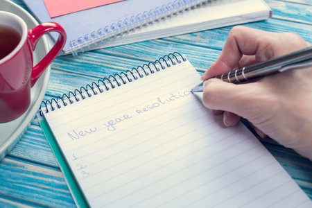 female hand writing about new year resolutions in a notebook