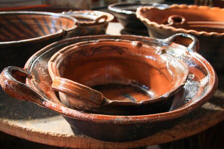 Traditional Brown Clay Cooking Pots Stacked up on Wood Tableの写真素材
