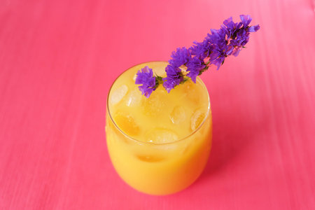 Fresh orange juice on pink background