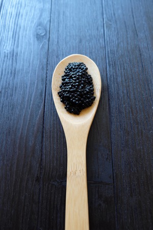 Black caviar in a large wooden spoonの写真素材