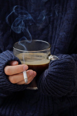 Cigarette and coffee in hand and blue sweaterの写真素材