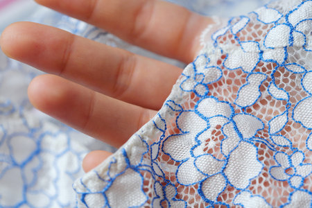 Beautiful delicate openwork white and blue lace in handの写真素材