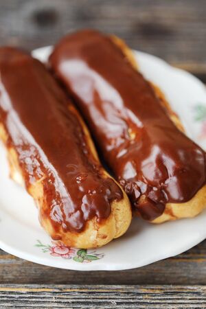Delicious eclairs with chocolate frosting on the tableの写真素材