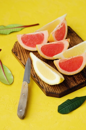 Grapefruit and lemon cut slices on yellow backgroundの写真素材