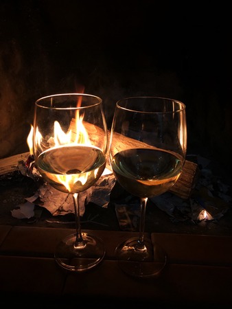 Two glasses of white wine by the fireplaceの写真素材
