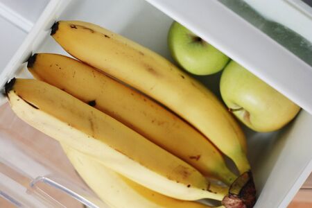 Fresh bananas and apples in the fridgeの写真素材