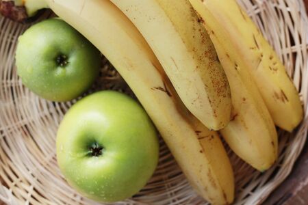 Green apples and bananas on the tableの写真素材