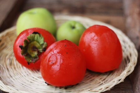 Delicious persimmon and green apples on the tableの写真素材
