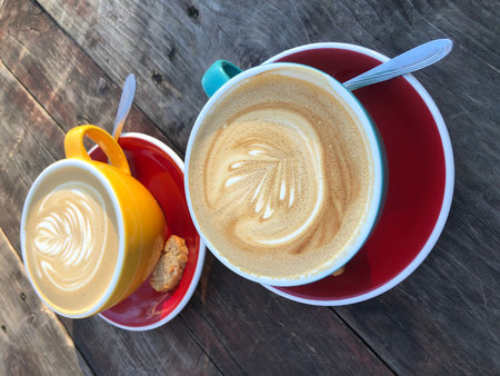 Two cups of latte art coffee on wooden table. Top view.