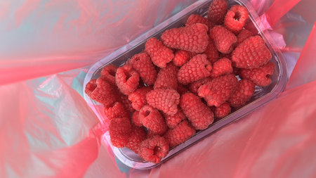 Fresh raspberries in plastic bag on pink background. Top view.の写真素材