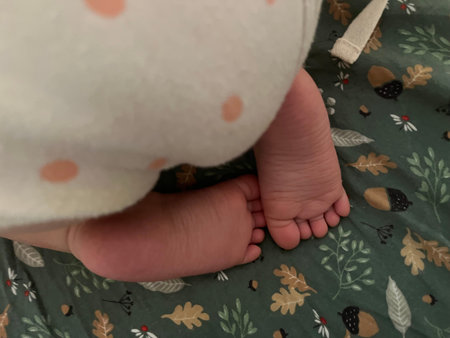 Baby feet on a green blanket with a polka dot pattern.