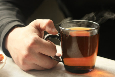 Cup of tea in the hands of a man on a black backgroundの写真素材