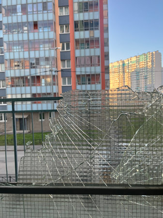 Fence with broken glass on the background of a modern apartment building
