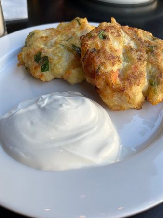 Potato pancakes with sour cream on a white plate in a restaurant