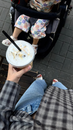 Coffee in a plastic cup with a woman sitting on the benchの写真素材