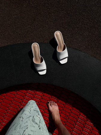 Women's feet in white sandals on a red brick background.の写真素材