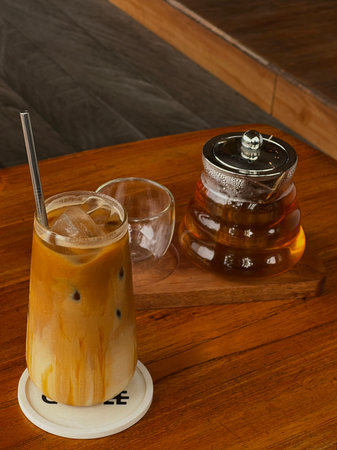Iced coffee in a glass with ice cubes on a wooden table