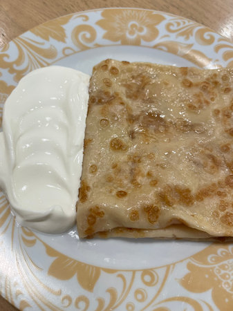 Pancakes with sour cream on a plate, close-up