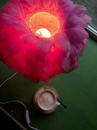 Cup of coffee and a lamp in the shape of a flowerの写真素材