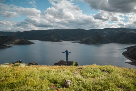 Young man with arms open enjoying a natural landscapeの写真素材