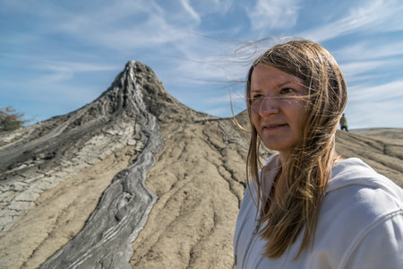 Young girl outdoors wearing sportswear with a mud volcano's crater in the background, Romaniaの写真素材
