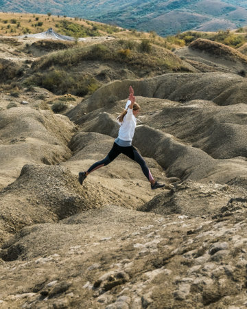 Young girl wearing sportswear outdoors in a jump, picture taken in the mud volcanoes park in Romaniaの写真素材