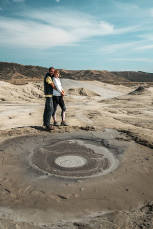 Young couple cuddling next to a mud volcano, Romaniaの写真素材