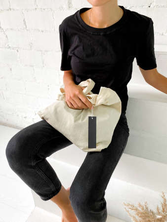 Beautiful young woman in black t-shirt and jeans holding a tote bag or shopper
