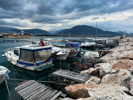 Quiet harbor with fishing boats and rocky shoreline at dusk in a coastal townの写真素材
