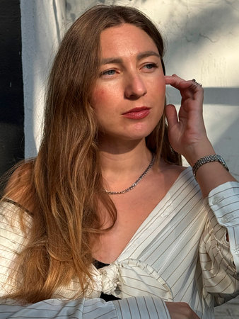 Woman with long hair poses thoughtfully in natural light at an outdoor location