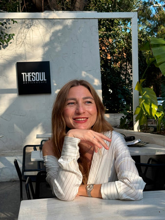 Young woman enjoying a meal at a stylish outdoor restaurant in a sunny setting