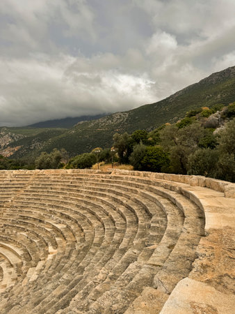 Historic ancient amphitheater surrounded by mountains on a cloudy day
