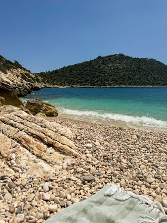 Pebbles cover the beach as turquoise waves gently crashの写真素材