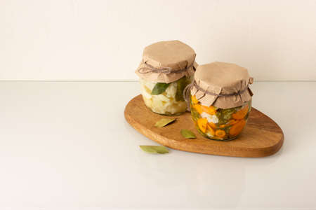 Canned vegetables in a jars: cauliflower, broccoli and carrot with spice on wooden board. White...